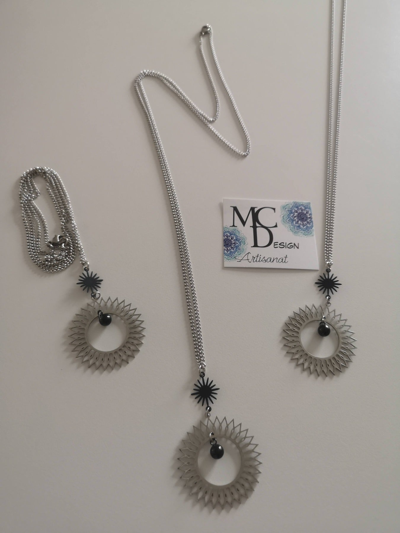 Magnifique collier long, fait avec 2 breloques soleil noir et argent. Collier très versatile et se porte avec beaucoup de style.