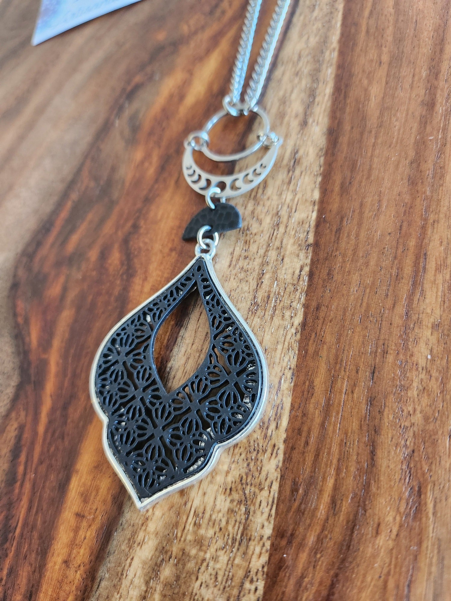 Superbe collier inox avec croissant de lune et breloques noires.