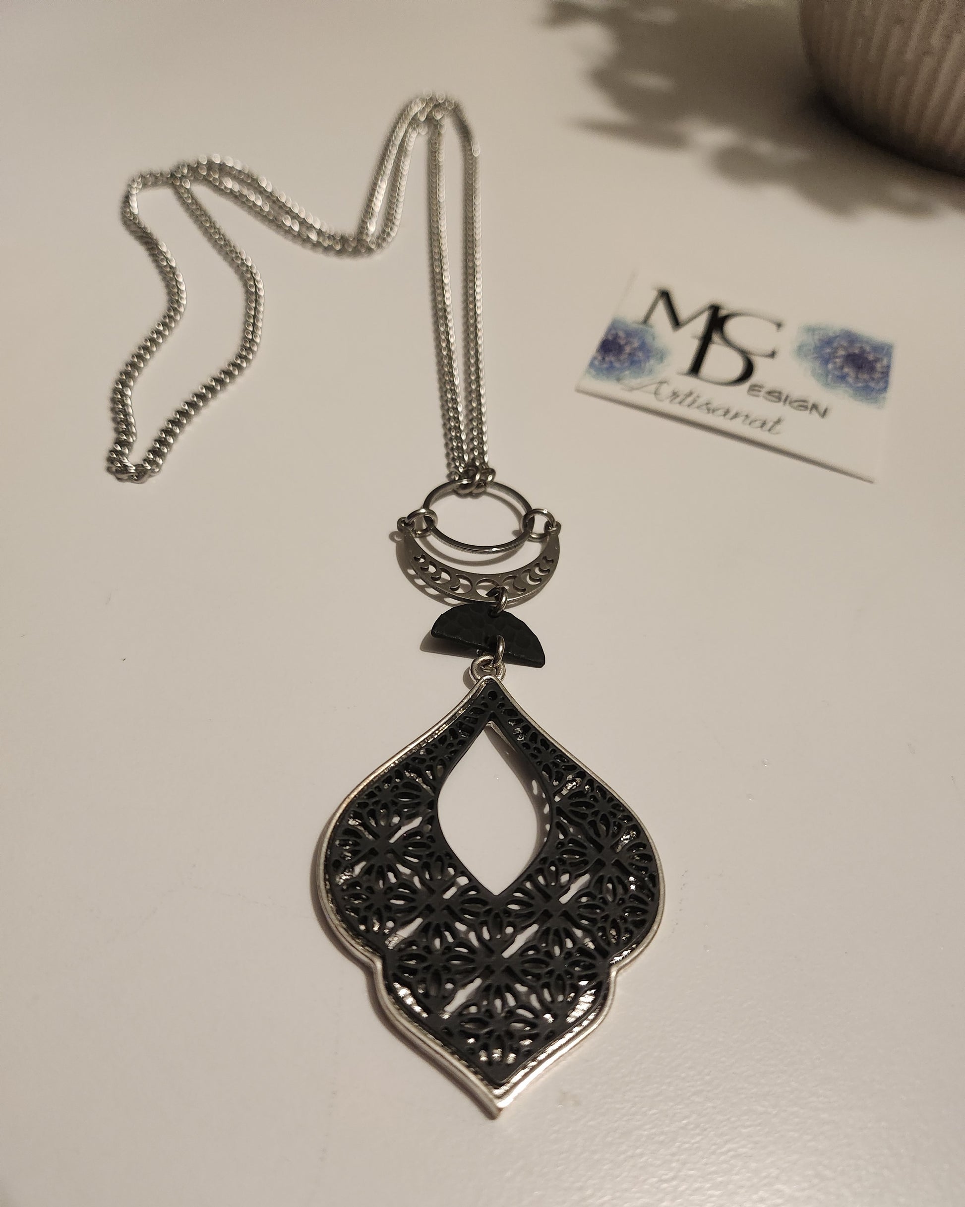 Superbe collier inox avec croissant de lune et breloques noires.
