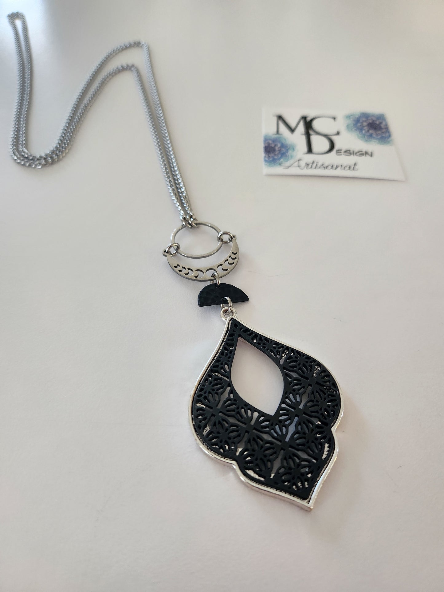 Superbe collier inox avec croissant de lune et breloques noires.