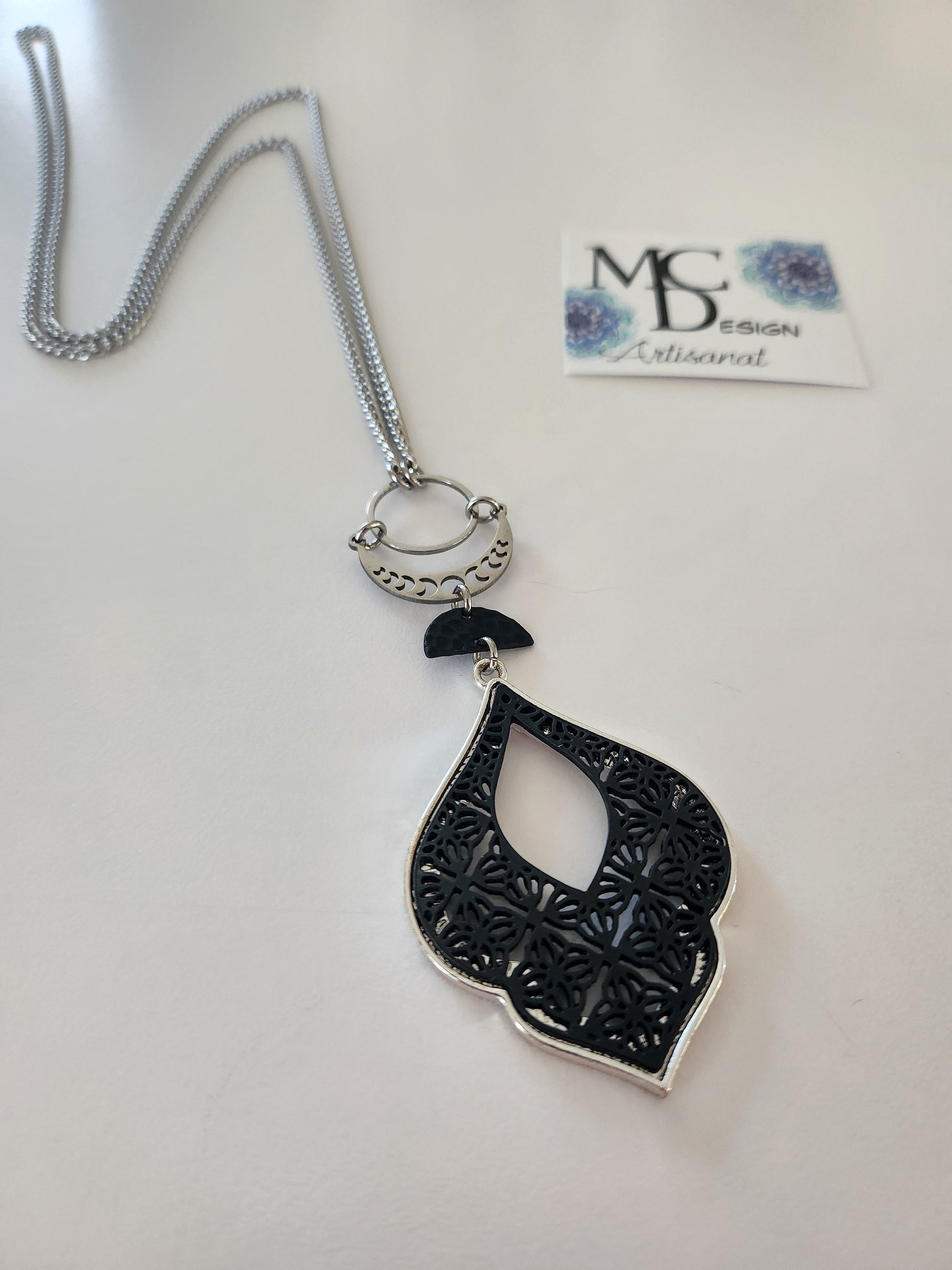 Superbe collier inox avec croissant de lune et breloques noires.
