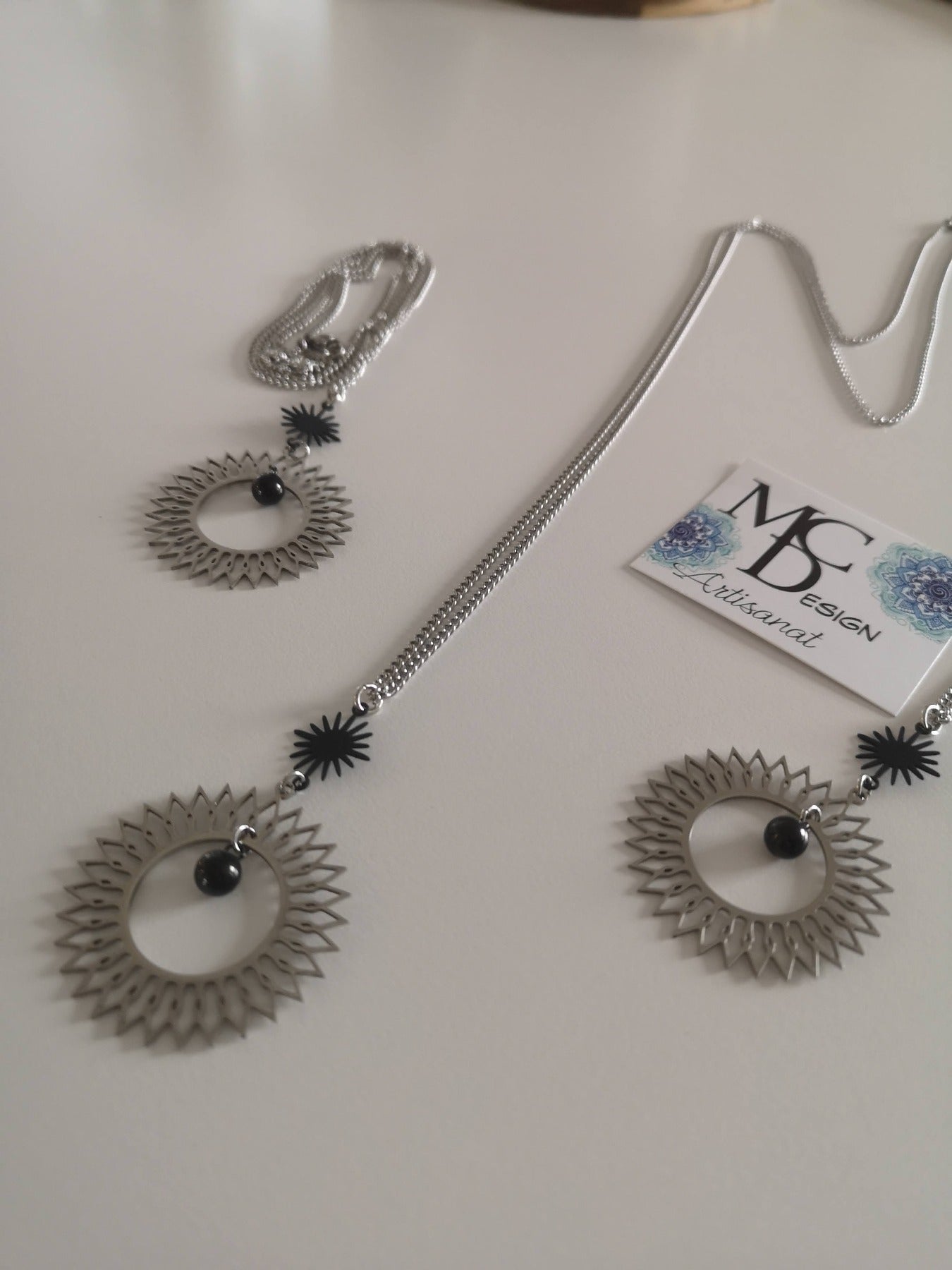 Magnifique collier long, fait avec 2 breloques soleil noir et argent. Collier très versatile et se porte avec beaucoup de style.